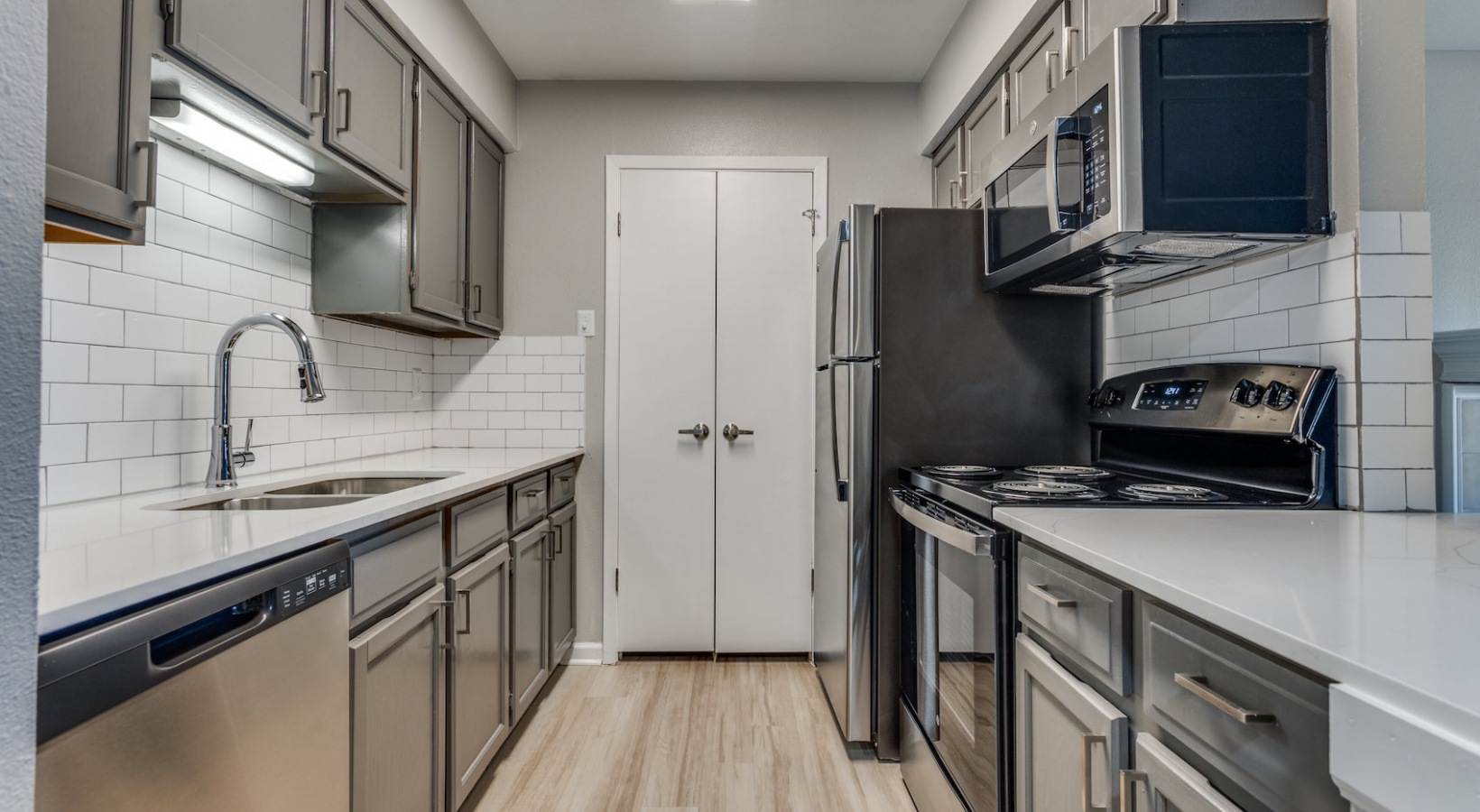 a kitchen with stainless steel appliances and wood floors at The Richmond